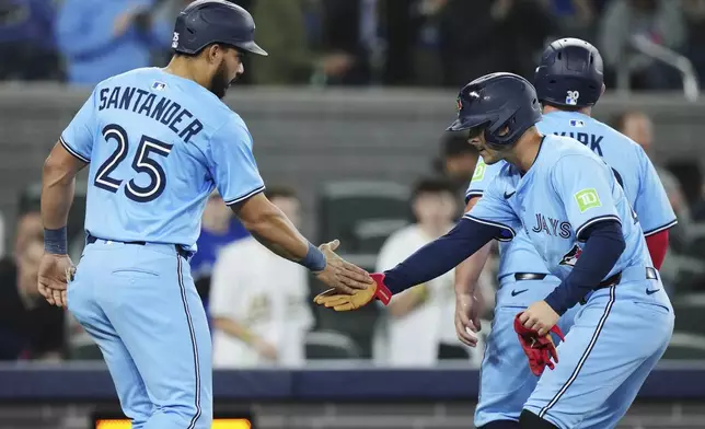 Toronto Blue Jays' Ernie Clement, right, celebrates his three-run home run against the Athletics with Anthony Santander (25) during the second inning of a baseball game in Toronto, Thursday, May 29, 2025. (Nathan Denette/The Canadian Press via AP)