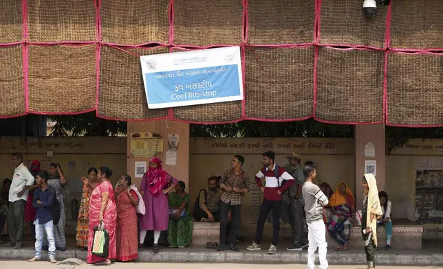People wait for a bus at a cool bus stop in Ahmedabad, India, Wednesday, April 2, 2025. (AP Photo/Ajit Solanki)
