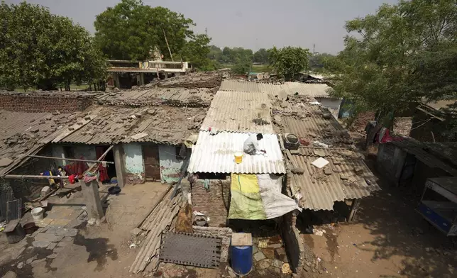 A man applies reflective paint to the roof of a house that helps keep the indoors cooler in Ahmedabad, India, Wednesday, April 2, 2025. (AP Photo/Ajit Solanki)
