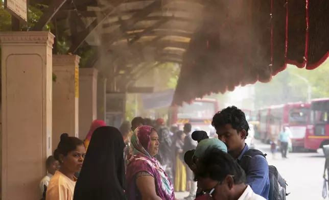 People wait for a bus at a cool bus stop in Ahmedabad, India, Wednesday, April 2, 2025. (AP Photo/Ajit Solanki)