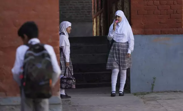 A Kashmiri school girl eats ice cream at a school after schools reopened, following a ceasefire agreement between India and Pakistan on Saturday, in Srinagar, Indian controlled Kashmir, Tuesday, May 13, 2025. (AP Photo/Mukhtar Khan)
