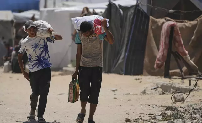 Palestinians carry food and humanitarian aid delivered by the U.S.-backed Gaza Humanitarian Foundation, after receiving the supplies in Rafah, as they arrive in Khan Younis, southern Gaza Strip, on Wednesday, May 28, 2025. (AP Photo/Abdel Kareem Hana)