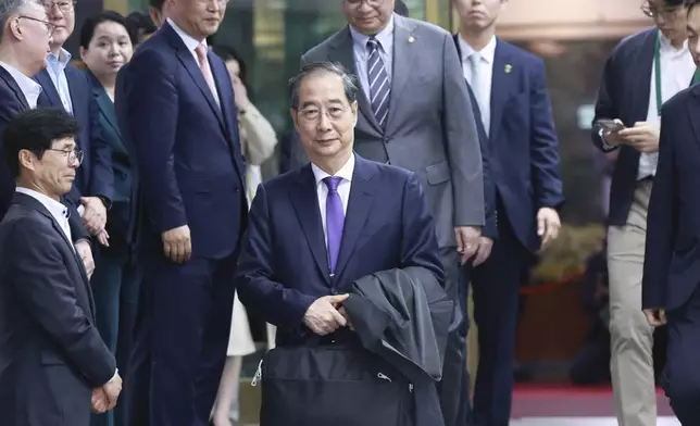 South Korean acting President Han Duck-soo, center, leaves after a press conference announcing his resignation at the Government Complex in Seoul, South Korea, Thursday, May 1, 2025. (Hong Hae-in/Yonhap via AP)