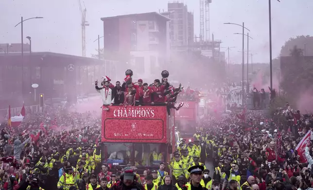 Liverpool players celebrate with the trophy on an open-top bus during the Liverpool FC Premier League victory parade in Liverpool, England, Monday, May 26, 2025.(AP Photo/Jon Super)