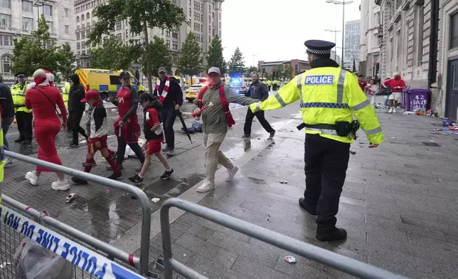Fans leave as Police and emergency personnel deal with an incident near the Liver Building during the Premier League winners parade in Liverpool, England, Monday, May 26, 2025.(AP Photo/Jon Super)