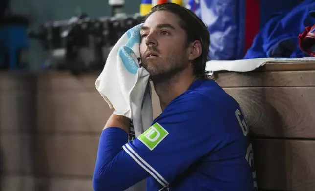 Toronto Blue Jays starting pitcher Kevin Gausman wipes sweat in the dugout during the fourth inning of a baseball game against the Texas Rangers, Monday, May 26, 2025, in Arlington, Texas. (AP Photo/Julio Cortez)
