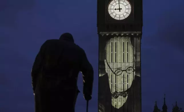 Images are projected onto the Queen Elizabeth Tower, in the Houses of Parliament, including the British World War II Prime Minister Winston Churchill, whose statue is in the foreground, during the V-E Day 80th anniversary events in London, Tuesday, May 6, 2025. (AP Photo/Alastair Grant)