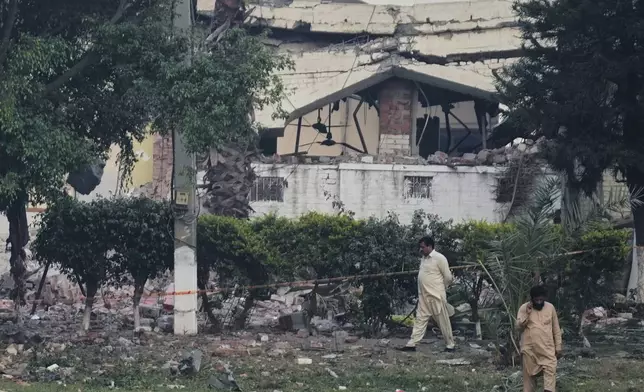 Local residents walk through rubble of a building damaged by a suspected Indian missile attack, in Muridke, a town in Pakistan's Punjab province, Wednesday, May 7, 2025. (AP Photo/K.M. Chaudary)