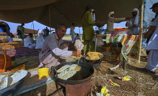 A vendor prepares traditional sweets called 'Jalebi' at his stall at the venue of a traditional bull race competition, in Malal, a village of Attock district, in Pakistan, Thursday, May 15, 2025. (AP Photo/Anjum Naveed)