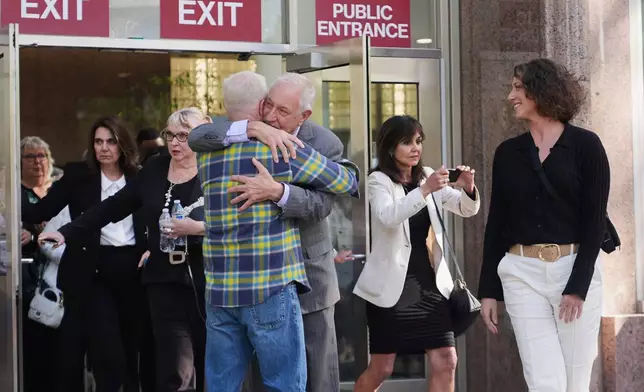 Attorney Mark Geragos, center, representing Erik and Lyle Menendez, gets a hug as leaves the courthouse after the brothers' resentencing hearing Tuesday, May 13, 2025, in Los Angeles. (AP Photo/Damian Dovarganes)