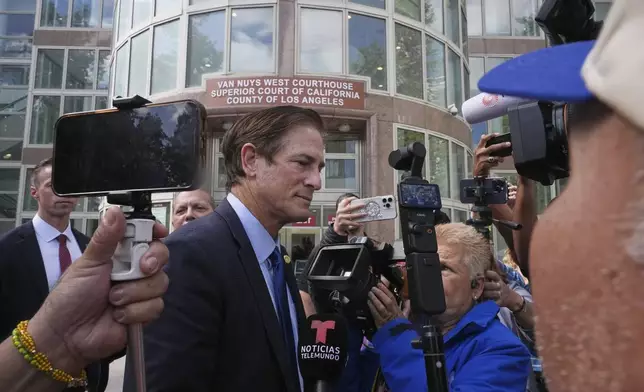 Los Angeles County District Attorney Nathan Hochman is surrounded by media outside the Van Nuys Courthouse during a hearing in the case of Erik and Lyle Menendez Tuesday, May 13, 2025, in Los Angeles. (AP Photo/Damian Dovarganes)