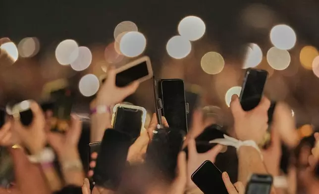 Mobile phones are held up as Zoe Me from Switzerland performs the song "Voyage" during the first semi-final of the 69th Eurovision Song Contest, in Basel, Switzerland, Tuesday, May 13, 2025. (AP Photo/Martin Meissner)