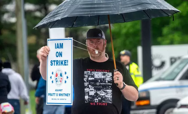 Andy Opgaard, a Pratt &amp; Whitney employee, blows a whistle and holds a sign as he crosses the street to with fellow workers on the picket line at the Silver Lane entrance in East Hartford, Conn., on the first day of their strike, Monday, May 5, 2025. (Aaron Flaum/Hartford Courant via AP)
