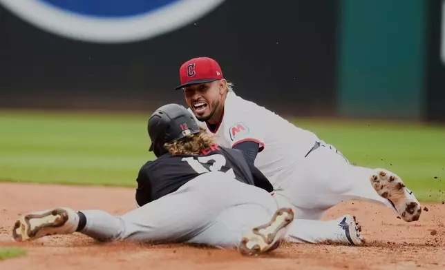 Minnesota Twins' Harrison Bader (12) slides safely into second base in front of Cleveland Guardians second baseman Gabriel Arias, rear, in the seventh inning of a baseball game in Cleveland, Thursday, May 1, 2025. (AP Photo/Sue Ogrocki)