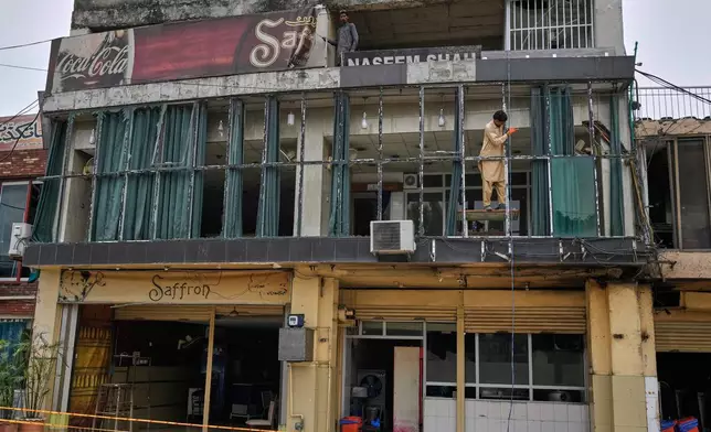 Workers repair broken glass of a building at the parking area of Rawalpindi Cricket Stadium, where a suspected Indian drone was crashed on Thursday, in Rawalpindi, Pakistan, Friday, May 9, 2025. (AP Photo/Anjum Naveed)