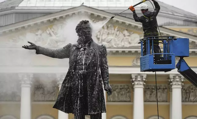 A worker cleans a statue of famous Russian poet Aleksander Pushkin in St. Petersburg, Russia, Monday, May 26, 2025. (AP Photo/Dmitri Lovetsky)