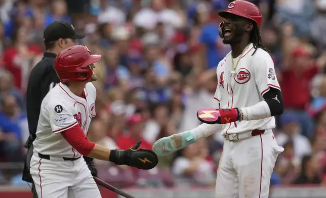 Cincinnati Reds' TJ Friedl, left, and Elly De La Cruz celebrate after scoring on a triple hit by Austin Hays in the fifth inning of a baseball game against the Chicago Cubs, Sunday, May 25, 2025, in Cincinnati. (AP Photo/Carolyn Kaster)