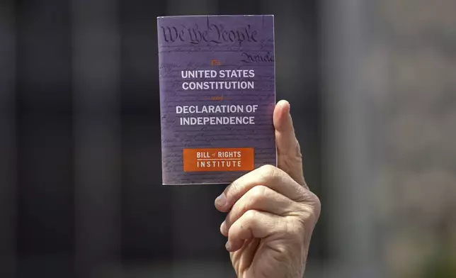FILE - A person holds a copy of the Constitution of the United States of America and Declaration of Independence at a May Day rally for the Rule of Law, May 1, 2025, in New York. (AP Photo/Adam Gray, File)
