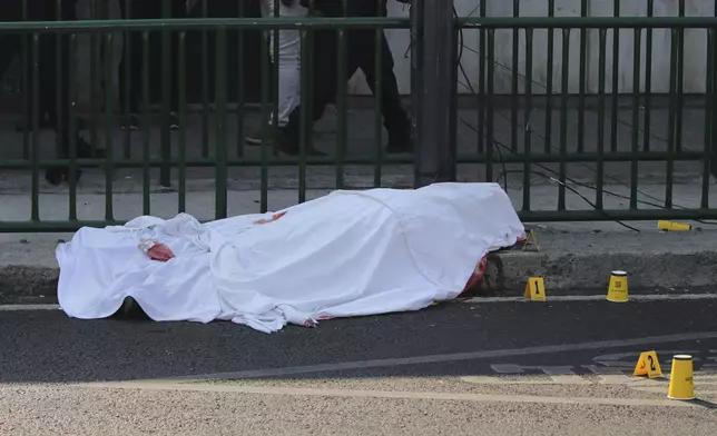 A body lies covered at the site where the personal secretary and an advisor to Mexico City's mayor were killed by gunmen on a motorcycle, in Mexico City, Tuesday, May 20, 2025. (AP Photo/Tristan Velazquez)