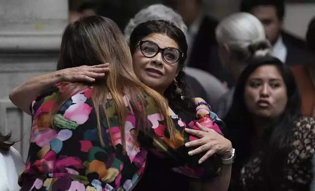 A staff member offers condolences to Mexico City Mayor Clara Brugada, facing camera, at a press conference where she spoke about the assassination of her personal secretary and one of her advisors who were killed earlier in the day by gunmen on a motorcycle, in Mexico City, Tuesday, May 20, 2025. (AP Photo/Marco Ugarte)