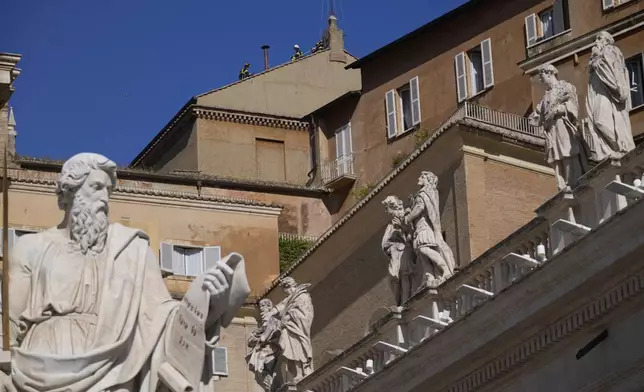Firefighters place the chimney on the roof of the Sistine Chapel, where cardinals will gather to elect the new pope, at the Vatican, Friday, May 2, 2025. (AP Photo/Gregorio Borgia)