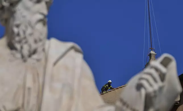 Firefighters place the chimney on the roof of the Sistine Chapel, where cardinals will gather to elect the new pope, at the Vatican, Friday, May 2, 2025. (AP Photo/Gregorio Borgia)