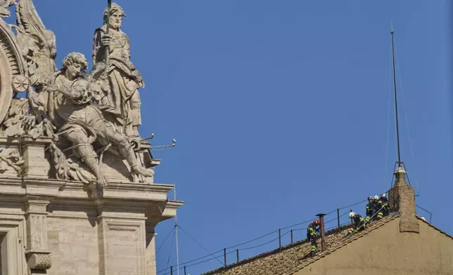 Firefighters place the chimney on the roof of the Sistine Chapel, where cardinals will gather to elect the new pope, at the Vatican, Friday, May 2, 2025. (AP Photo/Bernat Armangue)