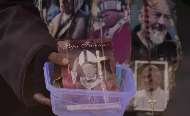 A woman begs for money outside St. Peter's square at the Vatican, Friday, May 2, 2025. (AP Photo/Gregorio Borgia)