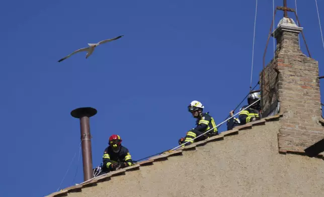 Firefighters place the chimney on the roof of the Sistine Chapel, where cardinals will gather to elect the new pope, at the Vatican, Friday, May 2, 2025. (AP Photo/Gregorio Borgia)