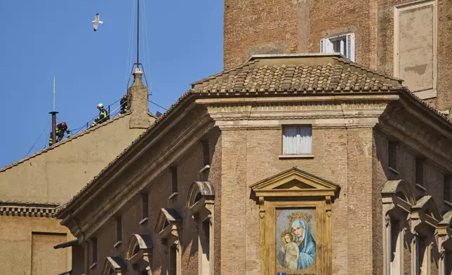 Firefighters place the chimney on the roof of the Sistine Chapel, where cardinals will gather to elect the new pope, at the Vatican, Friday, May 2, 2025. (AP Photo/Bernat Armangue)