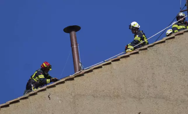 Firefighters place the chimney on the roof of the Sistine Chapel, where cardinals will gather to elect the new pope, at the Vatican, Friday, May 2, 2025. (AP Photo/Gregorio Borgia)
