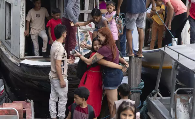 A girl embraces biologist Tatyanna Mariúcha, head of the Emilio Goeldi Museum's scientific base, as children arrive at the station in the Caxiuana National Forest in Para state, Brazil, Friday, March 21, 2025. (AP Photo/Jorge Saenz)