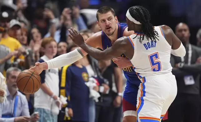 Denver Nuggets center Nikola Jokic, back, passes the ball as Oklahoma City Thunder guard Luguentz Dort defends in overtime of Game 3 in the Western Conference semifinals of the NBA basketball playoffs Friday, May 9, 2025, in Denver. (AP Photo/David Zalubowski)