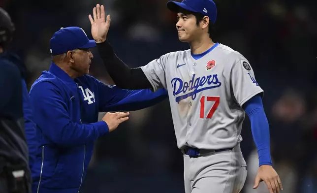Los Angeles Dodgers' Shohei Ohtani (17) is congratulated by manager Dave Roberts, left, after the team defeated the Cleveland Guardians in a baseball game, Monday, May 26, 2025, in Cleveland. (AP Photo/David Dermer)