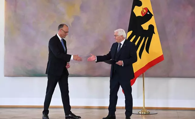 German President Frank-Walter Steinmeier, right, presents Federal Chancellor Friedrich Merz with his certificate of appointment at Bellevue Palace in Berlin, following his election by the German Bundestag, on Tuesday May 6, 2025. (Bernd von Jutrczenka/dpa via AP)