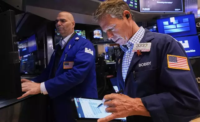 Specialist Philip Finale, left, and trader Robert Charmak work on the floor of the New York Stock Exchange, Friday, May 2, 2025. (AP Photo/Richard Drew)