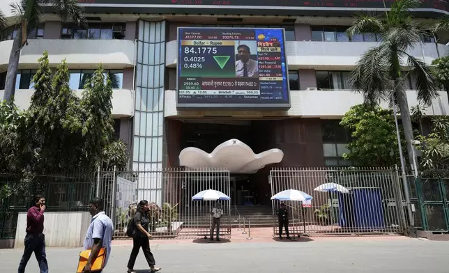 People walk past a live screen on the facade of Bombay Stock Exchange (BSE) building in Mumbai, India, Monday, May 5, 2025. (AP Photo/Rajanish Kakade)