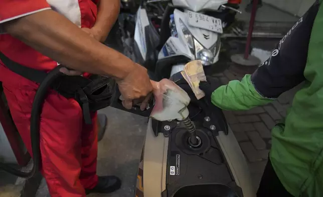 An employee fills up the tank of a customer's motorbike at a gas station in Jakarta, Indonesia, Monday, May 5, 2025. (AP Photo/Tatan Syuflana)