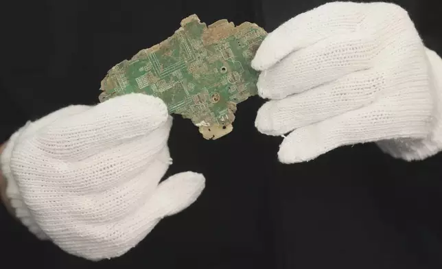 A Thai official shows a sample of illegally imported electronic waste from the United States which they said they seized at Bangkok Port during a press conference in Bangkok, Thailand, Wednesday, May 14, 2025. (AP Photo/Sakchai Lalit)