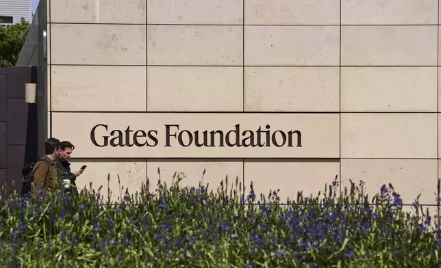 People walk by a Gates Foundation sign at the foundation's campus Wednesday, April 30, 2025, in Seattle. (AP Photo/Lindsey Wasson)