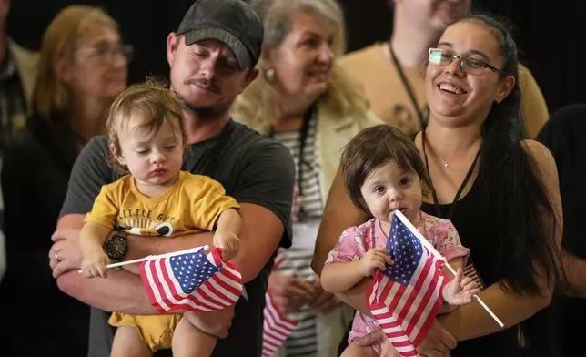 Afrikaner refugees from South Africa holding American flags arrive, Monday, May 12, 2025, at Dulles International Airport in Dulles, Va. (AP Photo/Julia Demaree Nikhinson)