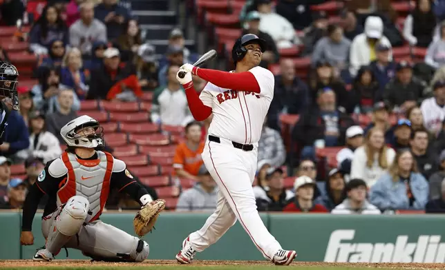 Boston Red Sox's Rafael Devers, right, follows through on a grand slam against the Baltimore Orioles during the eighth inning in the first baseball game of a doubleheader Friday, May 23, 2025, at Fenway Park in Boston. (AP Photo/Winslow Townson)