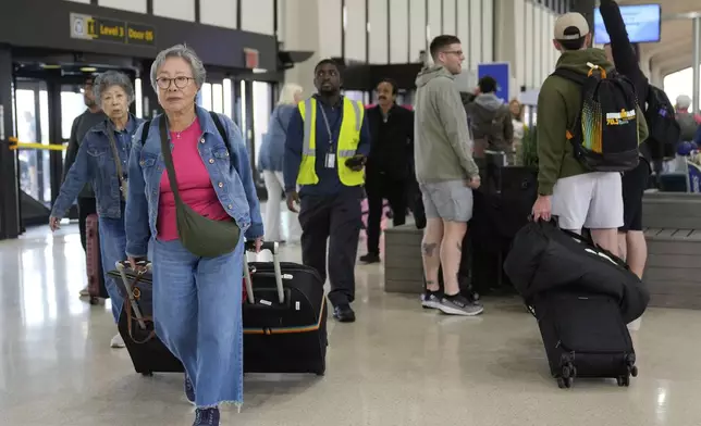 People prepare to board flights at Newark Liberty International Airport in Newark, N.J., Monday, May 5, 2025. (AP Photo/Seth Wenig)