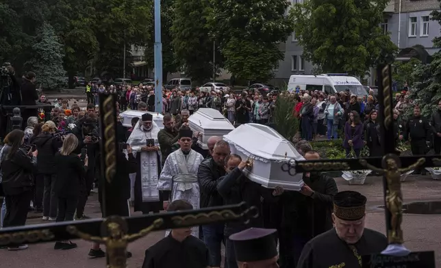 Funeral workers carry coffins during a funeral ceremony for Tamara Martyniuk, 8, Stanislav Martyniuk, 12, and Roman Martyniuk, 17, killed in a Russian strike on Sunday, in Korostyshiv, Zhytomyr region, Ukraine, Wednesday, May 28, 2025. (AP Photo/Evgeniy Maloletka)