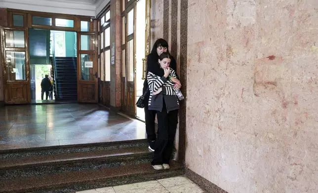 People cry during a funeral ceremony for Tamara Martyniuk, 8, Stanislav Martyniuk, 12, and Roman Martyniuk, 17, killed in a Russian strike on Sunday, in Korostyshiv, Zhytomyr region, Ukraine, Wednesday, May 28, 2025. (AP Photo/Evgeniy Maloletka)