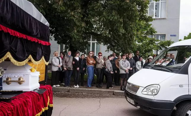 Local residents attand a funeral ceremony for Tamara Martyniuk, 8, Stanislav Martyniuk, 12, and Roman Martyniuk, 17, killed in a Russian strike on Sunday, in Korostyshiv, Zhytomyr region, Ukraine, Wednesday, May 28, 2025. (AP Photo/Evgeniy Maloletka)