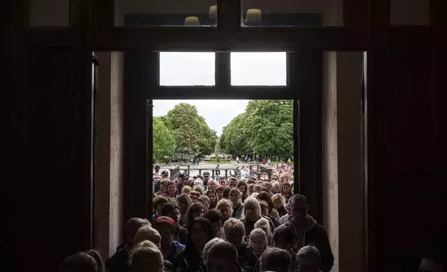 Local residents line up to enter a funeral ceremony for Tamara Martyniuk, 8, Stanislav Martyniuk, 12, and Roman Martyniuk, 17, killed in a Russian strike on Sunday, in Korostyshiv, Zhytomyr region, Ukraine, Wednesday, May 28, 2025. (AP Photo/Evgeniy Maloletka)