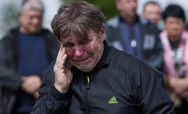 A father mourns his children Tamara Martyniuk, 8, Stanislav Martyniuk, 12, and Roman Martyniuk, 17, killed in a Russian strike on Sunday, during farewell ceremony in Korostyshiv, Zhytomyr region, Ukraine, Wednesday, May 28, 2025. (AP Photo/Evgeniy Maloletka)