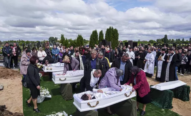 Relatives say goodbye to children Roman Martyniuk, 17, Tamara Martyniuk, 8, and Stanislav Martyniuk, 12, killed in a Russian strike on Sunday, during farewell ceremony in Korostyshiv, Zhytomyr region, Ukraine, Wednesday, May 28, 2025. (AP Photo/Evgeniy Maloletka)