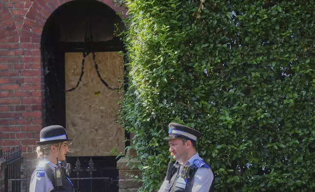 Police Community Support Officers stand near the fire damaged doorway of a house belonging to British Prime Minister Keir Starmer in Kentish Town in London, Tuesday, May 13, 2025. (AP Photo/Kirsty Wigglesworth)